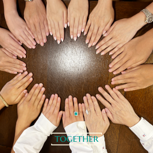 Hands joined in a circle on a wooden table, captioned Together — cover art from T's Human Pace visual essays